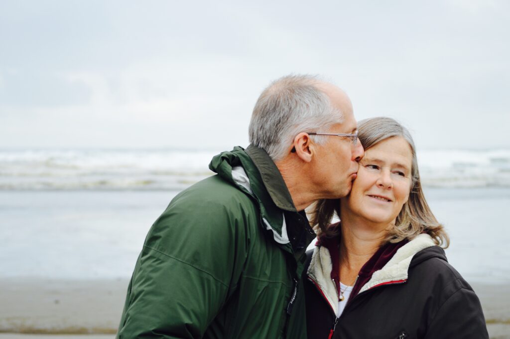Elderly man kissing his elderly wife on the beach