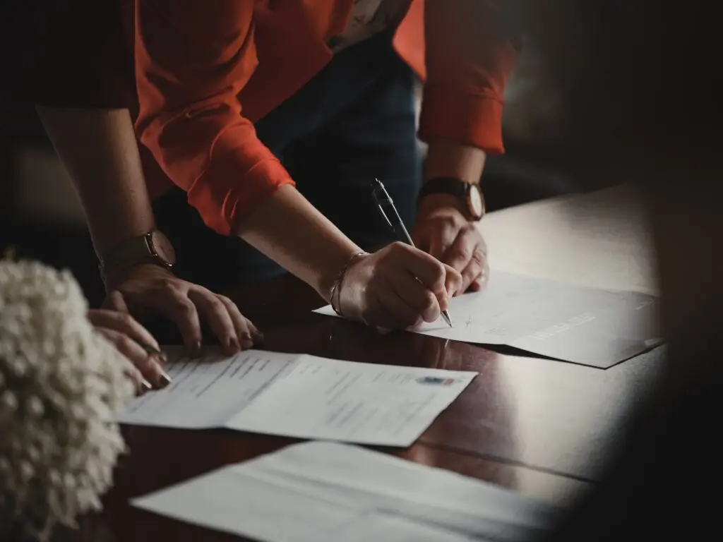 Men signing documents with a notary on a wood table