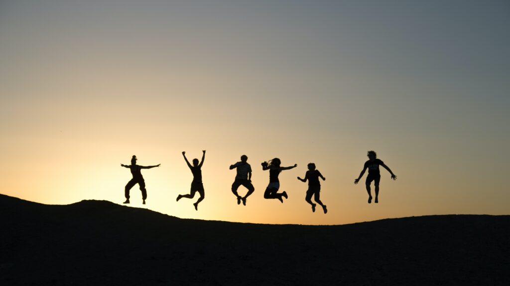 Silhouettes of people jumping in the air at sunset